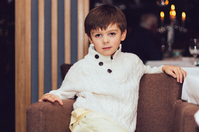 Portrait of cute boy sitting on sofa at home