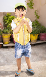 Full length portrait of boy holding yellow while standing outdoors