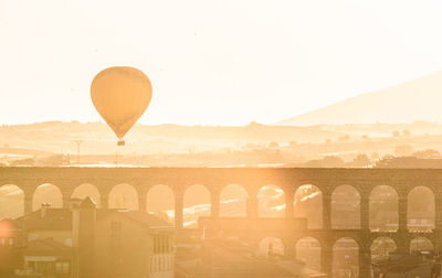 Hot air balloon flying against sky during sunset over the romanic acueduct of segovia.