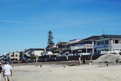 People on beach against clear blue sky