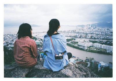 Rear view of people looking at cityscape against sky