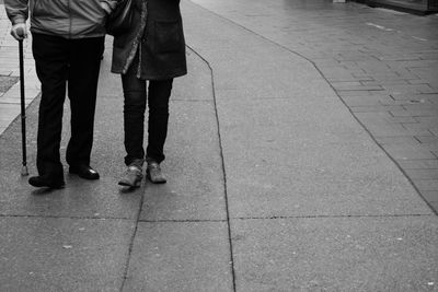 Low section of couple walking on sidewalk