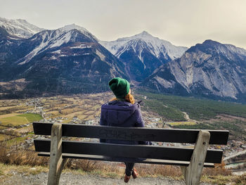 Rear view of woman sitting on mountain