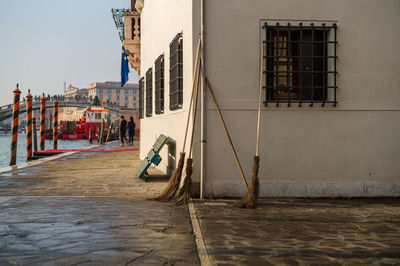 Three brooms made of straw lean against a house wall for cleaning up the traces of tourists.