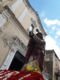 Low angle view of people standing by building against sky