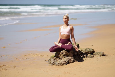 Full length of woman doing yoga at beach