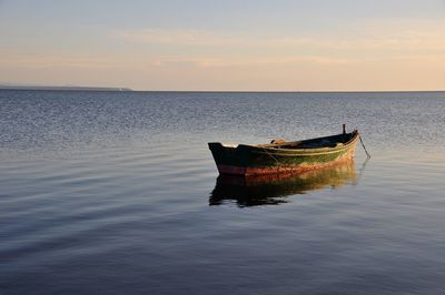 Boat in sea against sky during sunset