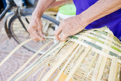 Close-up of man weaving wicker basket