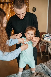 Mom and dad put on clothes for the child. high quality photo