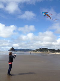 Full length of boy flying over beach against sky