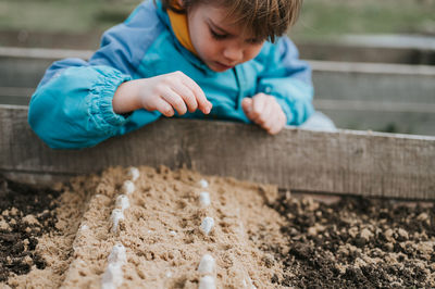 Spring planting seeding farm garden. little kid boy farmer gardener plants sow vegetable seeds soil