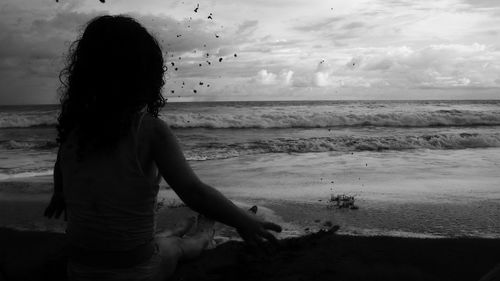 Rear view of woman on beach against sky