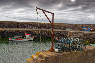 Fishing boats moored at harbor against sky