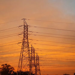 Low angle view of electricity pylon at sunset