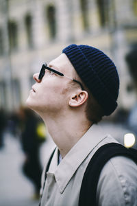 Close-up of teenage boy looking away while standing in city