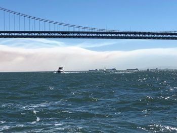 Suspension bridge over sea against sky
