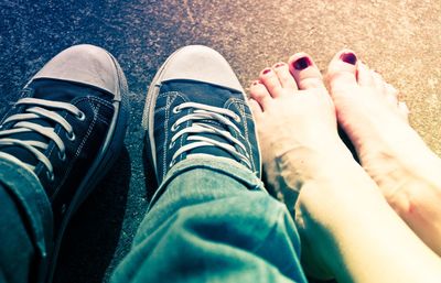 Low section of couple sitting on footpath