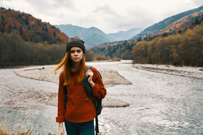 Portrait of young woman standing against mountains