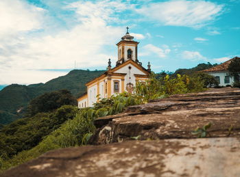 Low angle view of church and mountains against cloudy sky