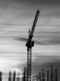 Low angle view of cranes at construction site against sky