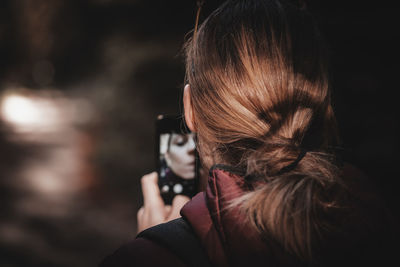 Rear view of woman photographing outdoors