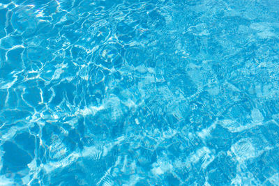 View of surface of turquoise water in swimming pool, summer background. gradient of color with waves