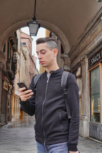 Young man using mobile phone standing in city