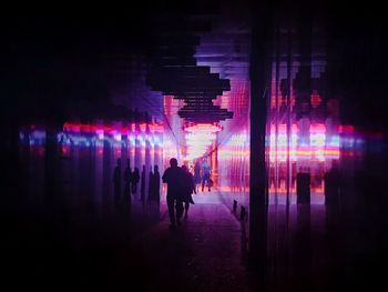 Silhouette people walking on illuminated street at night