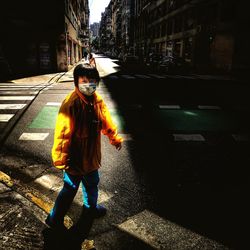 Rear view of girl walking on road in city
