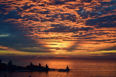 Silhouette people on beach against sky during sunset