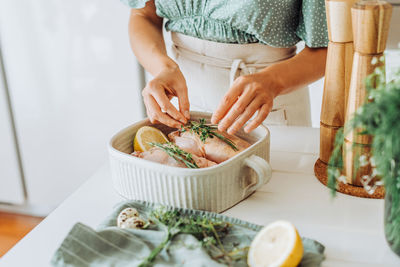 Female hands adding aromatic herbs to chicken for roasting