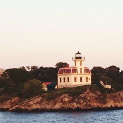 Lighthouse by sea against clear sky