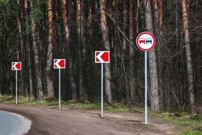 Road sign by trees in forest