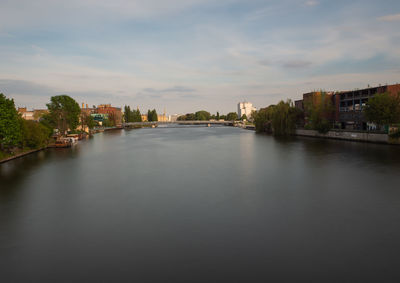 Buildings by river against sky in city