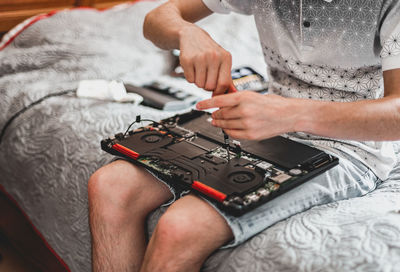 A young man is changing the thermal paste on a laptop.