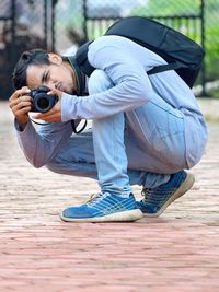 Full length of man photographing on footpath