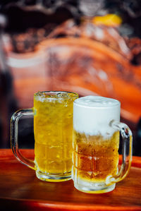 Butter beer and chrysanthemum tea in tall glass on wood table.