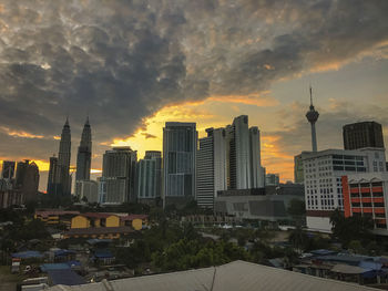 Buildings in city against cloudy sky during sunset