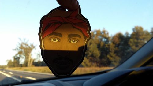 Close-up of man driving car against sky