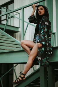 Full length of woman holding railing at staircase