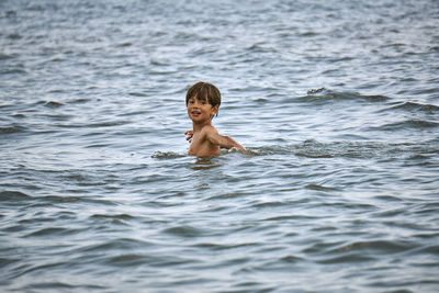 Portrait of shirtless boy swimming in sea
