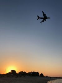 Low angle view of silhouette airplane against clear sky during sunset