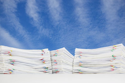 Low angle view of papers on table against blue sky
