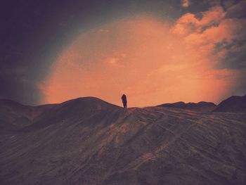 Silhouette woman standing on sand dune against sky