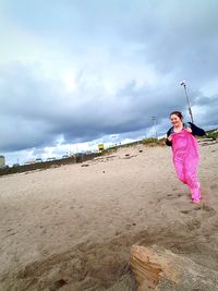 Girl standing on beach against sky