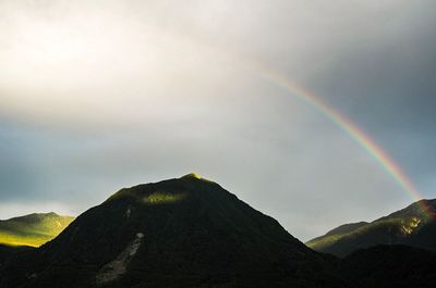 Low angle view of rainbow over mountains against sky