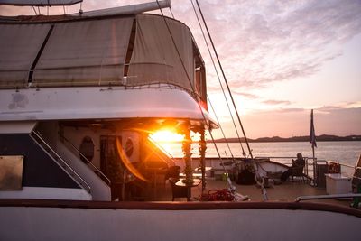 Sailboats moored on sea against sky during sunset