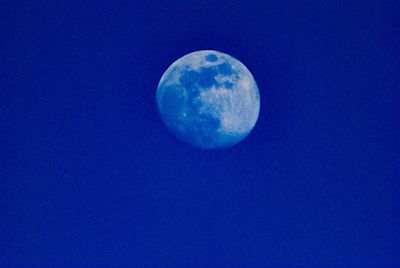 Low angle view of moon against blue sky