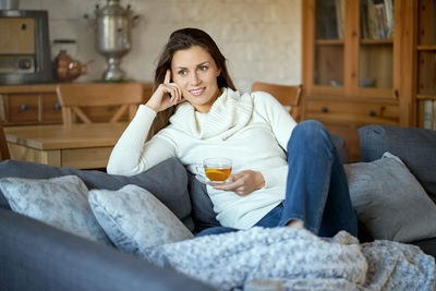 Woman having herbal tea on sofa at home