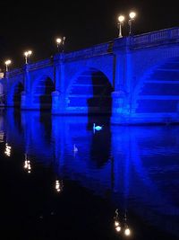 Illuminated bridge over river against sky at night